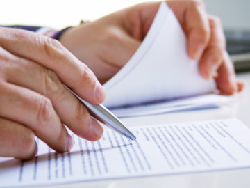 Hands of Business man in dark suit writing in his datebook