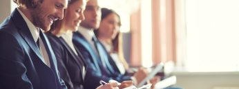 Row of business people making notes at seminar with young man on foreground